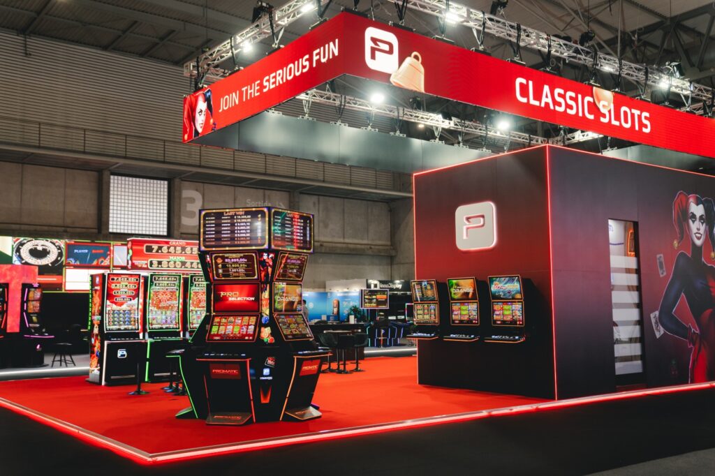 Stoisko Promatic Group na ICE Barcelona z podwieszeniem LED, automatami do gier i zamkniętą zabudową z grafiką
